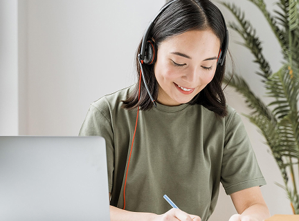 ヘッドセットをつけてパソコンで学習する女性の写真